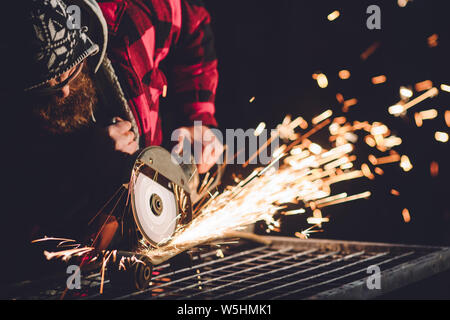 Worker Using Angle Grinder in Factory and throwing sparks. Stock Photo