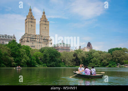 New York park, view in summer of people rowing boats on Central Park lake with the San Remo building in the background, Manhattan, New York City, USA. Stock Photo