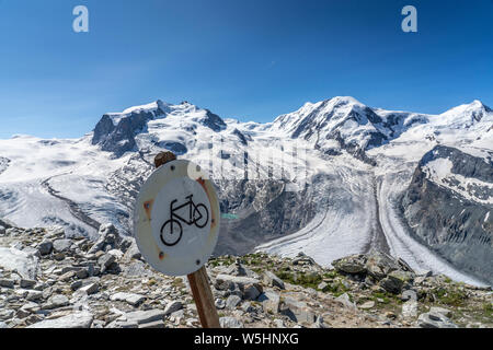 active senior woman, riding her electric mountainbike on the Gornergrat in Zermatt, Wallis,Switzerland. In The background Gorner Glacier, Monte Rosa Stock Photo
