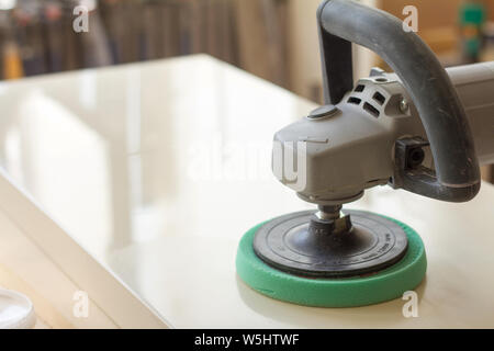 A carpenter polishes the surface of the facade before assembling furniture on a blurred background carpentry workshop, selective focus Stock Photo