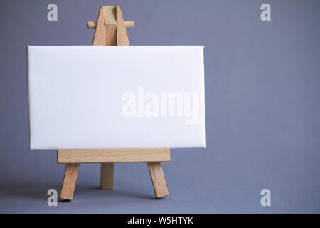 Miniature easel with a white board for writing, pointer on white surface, concept of direction and graphics, selective focus Stock Photo