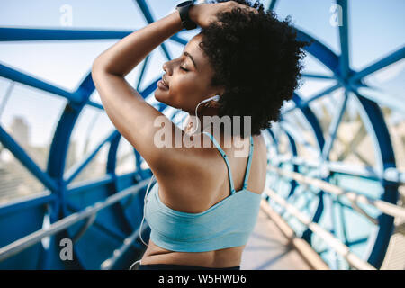 African american woman in fitness wear taking a break from workout and relaxing. Athletic woman relaxing outdoors after exercising. Stock Photo