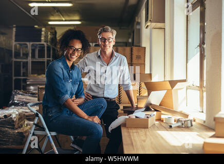 Successful online shop business partners in a small office. Male and female entrepreneurs at their online shop warehouse looking at camera and smiling Stock Photo