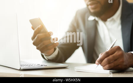 African American businessman noting information from cellphone Stock Photo