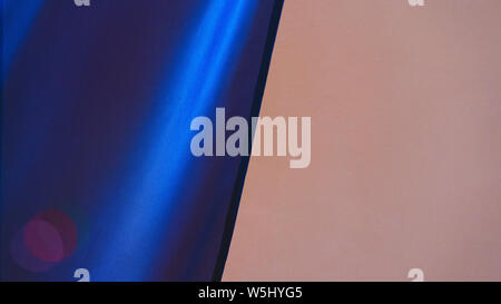 Blue fabric with color highlights on the background of the beige wall of the building Stock Photo