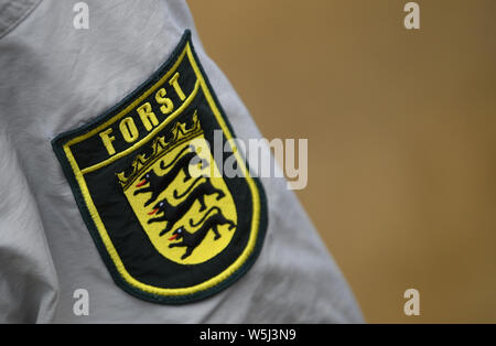 Waldshut Tiengen, Germany. 29th July, 2019. The logo of the Baden-Württemberg forest is sewn onto the sleeve of a shirt. Forest Minister Hauk (CDU) has called on forest owners to step up the fight against the bark beetle. They would now have to check their heat-damaged forests on a weekly basis. Credit: Patrick Seeger/dpa/Alamy Live News Stock Photo