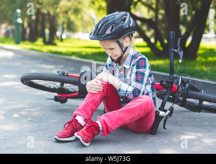 Crying girl is sitting next to her bike Stock Photo