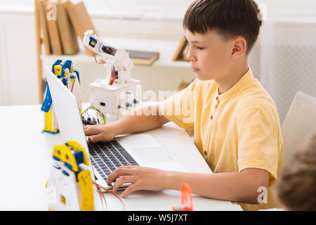 Schoolboy creating robotics project, typing plan in laptop Stock Photo