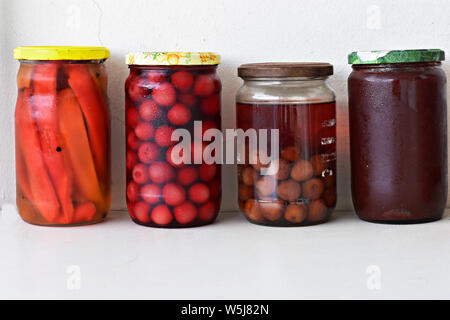 Variety of preserved food in glass jars - jam, marmalade, cherries, red pepper Preserving vegetables and fruits. Fermented food. Autumn canning. Stock Photo