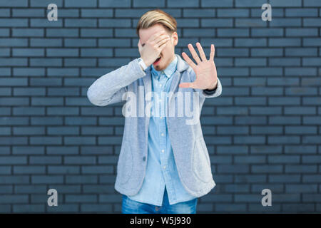 I don't want to look at this. Portrait of ignoring handsome young blonde man in casual style standing, closed his eye and showing stop sign gesture. i Stock Photo