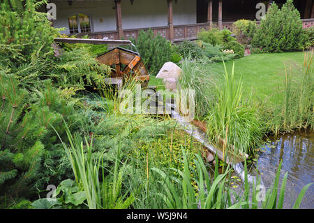 Landscape and arrangement. Driving mill wheel with falling water in the garden. Stock Photo