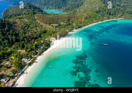 Aerial drone view of traditional fishing boats moored over a coral reef around a remote, green tropical island in the Mergui Archipelago Stock Photo