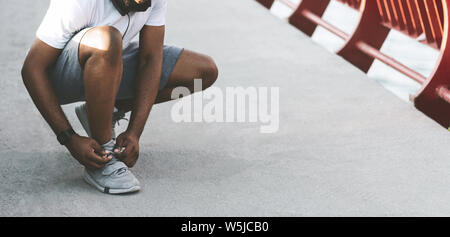 Black sporty man checking on his shoelaces Stock Photo