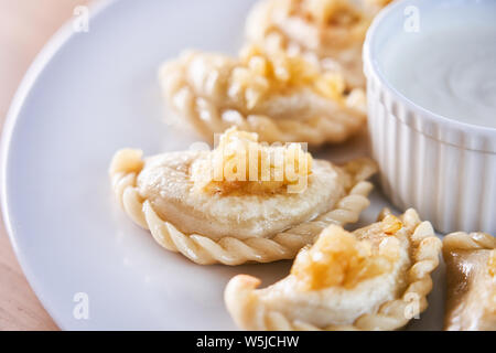 Picture of fried dumplings stuffed with meat sprinkled with carmelized onion on a white plate Stock Photo