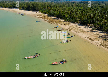 Aerial view of colorful traditional Longtail boats moored off a tropical beach in Thailand