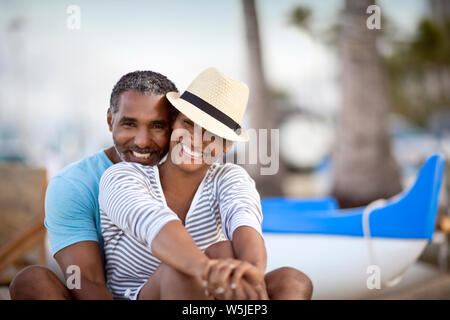 Portrait of mature couple relaxing happily together on beach. Stock Photo