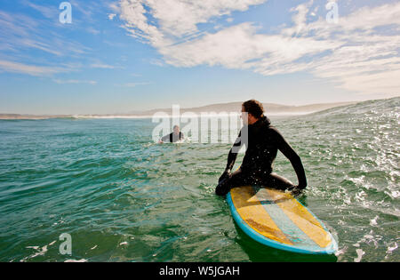 Two surfers heading out to catch some waves. Stock Photo