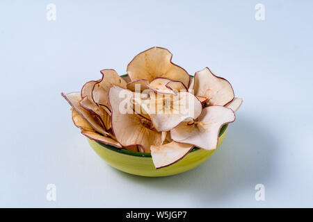 Flat lay Dried apple chips in a bowl over light blue background. Stock Photo