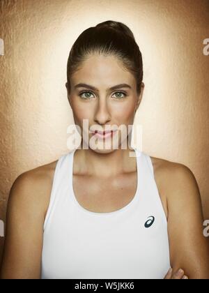 Portrait of female British Tennis player Jo Konta against a gold background in a studio