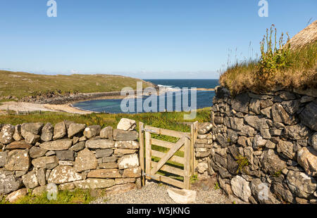 wide angel view trough a wooden garden gate down  to a sandy bay on the isle of lewis in Scotland on a sunny day Stock Photo