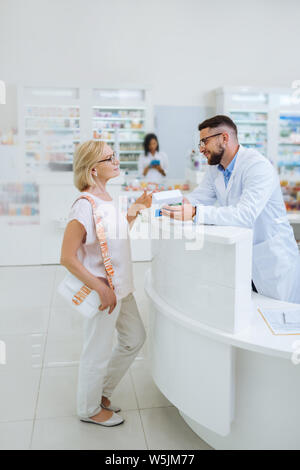 Pretty blonde female person talking to pharmacist Stock Photo