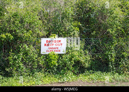 Padstow, Cornwall, England, May 2019, A red warning sign fixed to a fence at the edge of a cliff. Stock Photo