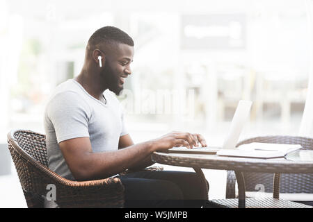 African businessman typing on laptop and listening to music Stock Photo