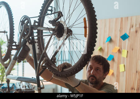 Man repairing old hardtail mountain bike in workshop, selective focus Stock Photo