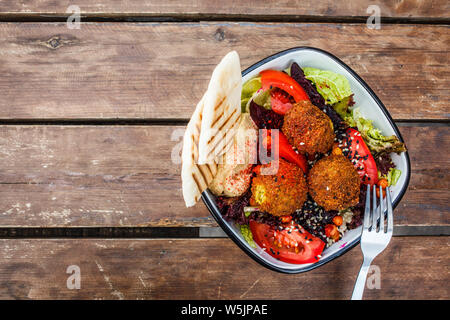 Israeli street food. Falafel salad with hummus, beetroot and vegetables in a bowl in a restaurant. Stock Photo