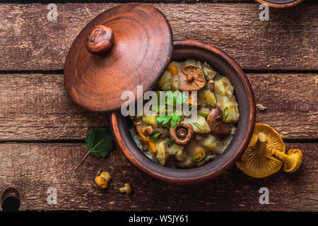 Stewed potato and mushrooms in a ceramic pot, top view, copy space Stock Photo