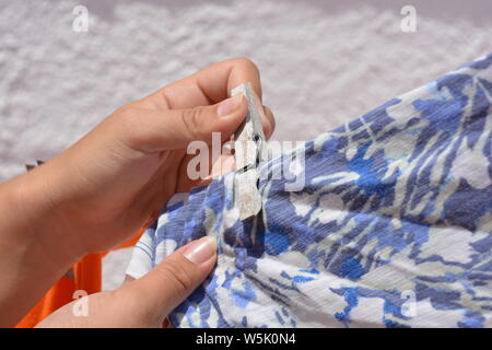 Young woman putting clean laundry  on the washing line, selective focus of peg in hand Stock Photo