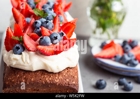 Summer dessert with strawberries and blueberries.  Cake loaf with buttercream icing and topped with fresh ripe summer colorful fruits and berries, sel Stock Photo