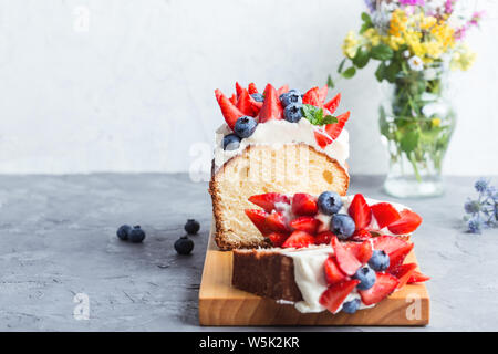 Summer dessert with strawberries and blueberries.  Buttercream berry pound cake with slices, colorful fruits and berries on top, selective focus, clos Stock Photo