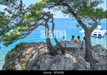 Unrecognizable tourists enjoy the sea vi at Brela. The Makarska riviera in Croatia is famous for its beautiful pebbly beaches and crystal clear water. Stock Photo