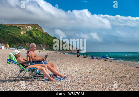 In late July, a couple relax on the beach at Seaton in South East Devon. Stock Photo