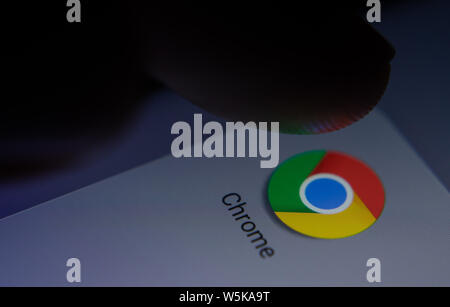 Chrome app icon on the smartphone screen with visible pixels and the finger about to launch it. Stock Photo