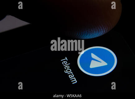 Telegram app icon on the smartphone screen with visible pixels and the finger about to launch it. Stock Photo