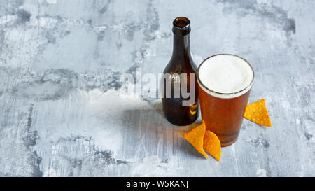 Glass of light beer on white stone background. Cold alcohol drink and snacks are prepared for a big friend's party. Concept of drinks, fun, food, celebrating, meeting, oktoberfest. Stock Photo