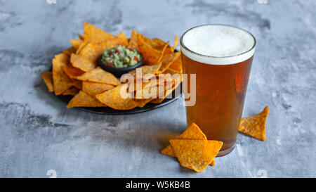 Glass of light beer on white stone background. Cold alcohol drink and snacks are prepared for a big friend's party. Concept of drinks, fun, food, celebrating, meeting, oktoberfest. Stock Photo