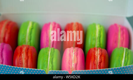 Twelve brightly coloured macaroons in a cardboard box shot close up. Stock Photo