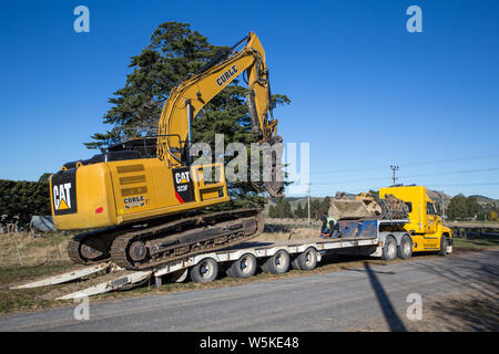 Sheffield, Canterbury, New Zealand, July 10 2019: A digger is transported by a large truck to a work site in a rural area Stock Photo