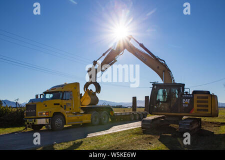 Sheffield, Canterbury, New Zealand, July 10 2019: A digger is transported by a large truck to a work site in a rural area Stock Photo