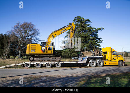 Sheffield, Canterbury, New Zealand, July 10 2019: A digger is transported by a large truck to a work site in a rural area Stock Photo