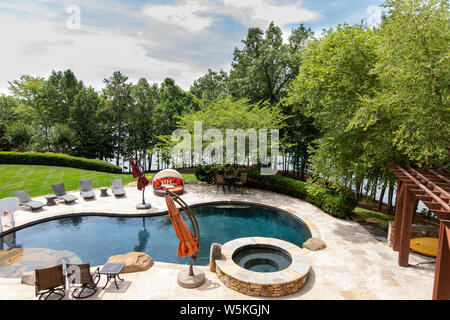 Luxurious outdoor pool with landscaping, in the backyard of a home, overlooking lake. Stock Photo