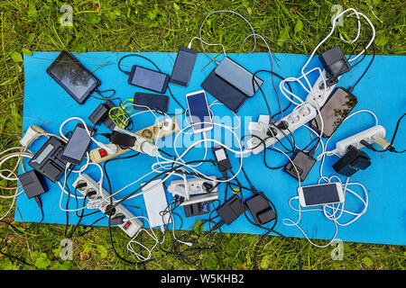 A lot of batteries, chargers for smartphones and electrical extension cords with electric devices, screens up, which are charged by them, they lie on Stock Photo