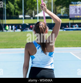 A high school girl holding a javelin overhead as she gets ready to compete in a track and field event. Stock Photo