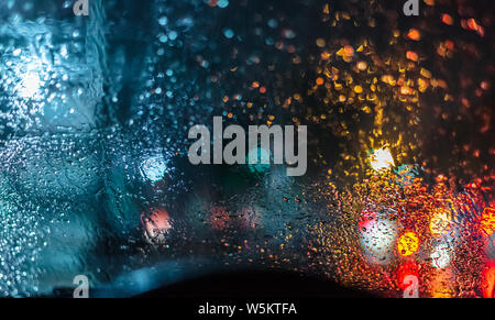 Street lights bokeh and Blurry Raindrops on the windshield of a car for background usage. Stock Photo