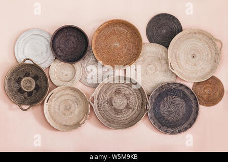 Wall decorated with different wicker handmade trays and baskets. Eco style and concept, Moroccan culture. Stock Photo