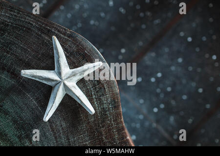 Dark background with one white handmade star, empty place and copy space. Eco concept. Wooden element in home decor and furniture. Stock Photo