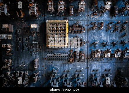 Vintage electrical control panel with rusted switches and gauges in an abandoned industrial facility Stock Photo